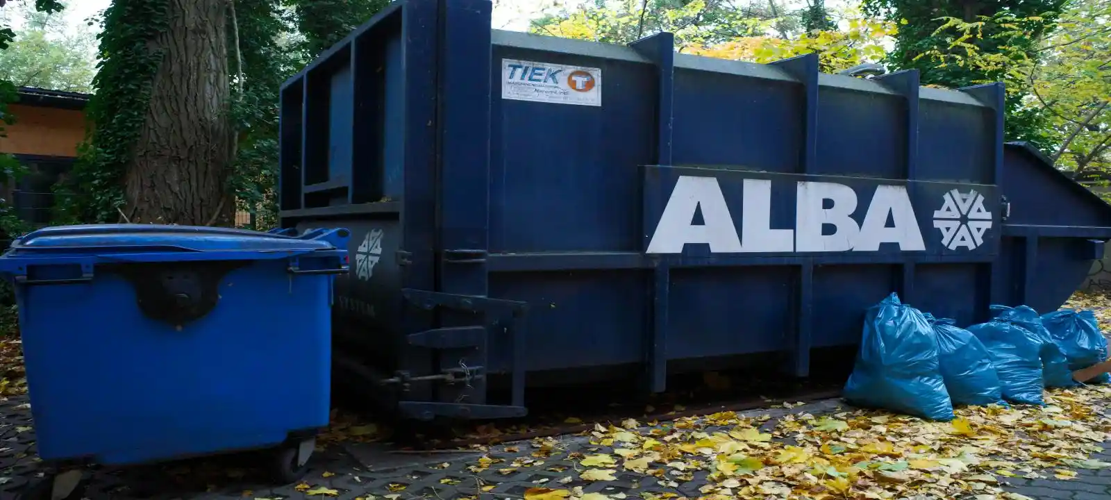 A large, convenient blue skip bin with several bags of rubbish placed outside it in Wollongong.