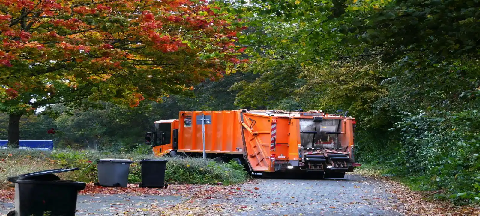 An orange garbage truck collecting bins for a rubbish removal service in Wollongong.